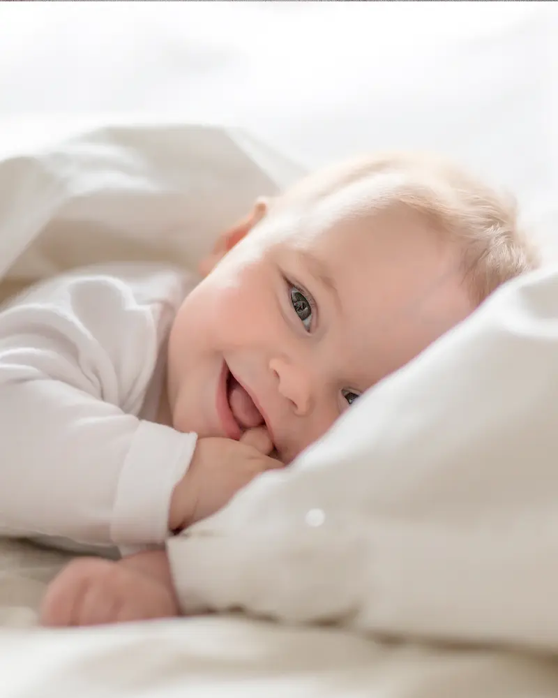 Baby laying in bed smiling.