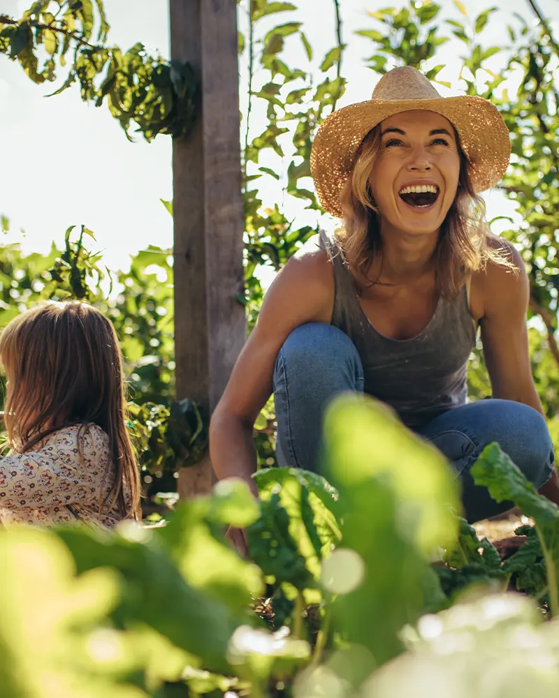 Woman and daughter sitting in garden smiling.